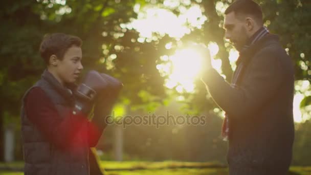 Vader leert zijn zoon boksen. Plezier doen in het Park. — Stockvideo
