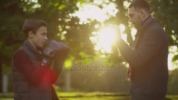 Pai ensina seu filho boxe. Diversão fazendo no parque . — Vídeo de Stock