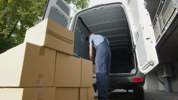 Jovem carregador coloca caixas em seu veículo comercial . — Vídeo de Stock