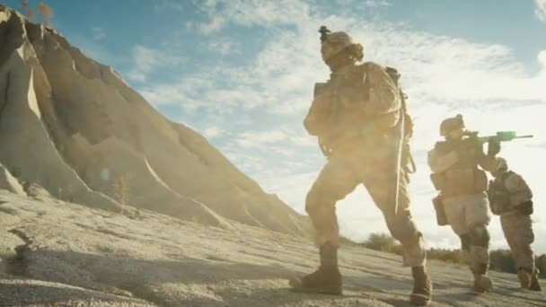 Escuadrón de soldados totalmente equipados y armados caminando en un solo archivo en el desierto. Moción lenta . — Vídeos de Stock