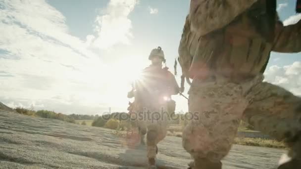 Trupp voll ausgerüsteter und bewaffneter Soldaten, die in einer einzigen Datei in der Wüste laufen. — Stockvideo