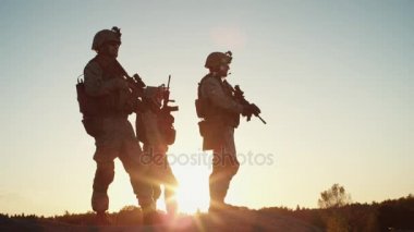 Takımı üç tam donanımlı ve silahlı askerler Hill çöl ortamında'nde Günbatımı ışık tutuyoruz. Ağır çekim.