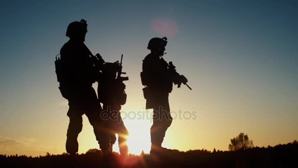 Отряд из трех полностью экипированных и вооружённых солдат, стоящих в пустыне в солнечном свете. Slow Motion . — стоковое видео