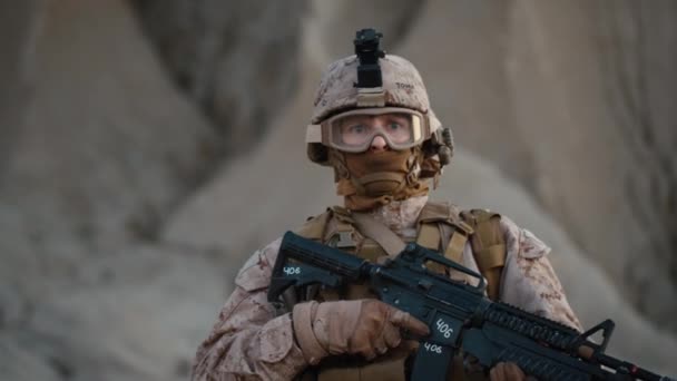 Портрет полностью экипированного и вооруженного солдата в защитных очках в пустыне — стоковое видео