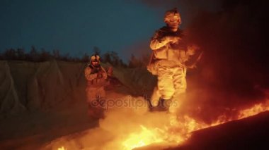 Grup silahlı asker ateşlerde gece askeri işlem sırasında çalışıyor. Ağır çekim.