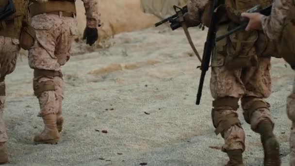 Grupo de soldados totalmente equipados e armados que caminham para a frente câmera externa no ambiente do deserto . — Vídeo de Stock