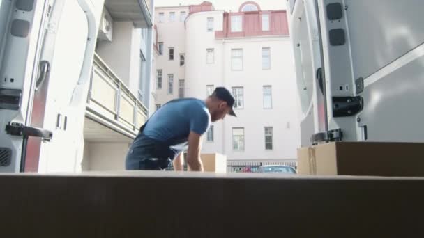 Jeune livreur accumule des boîtes en carton dans son véhicule commercial et couvre avec eux la caméra .