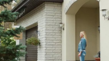 Uçak uçan onun posta paketi ona sunarken gülümseyen kadın bir verandada duruyor.