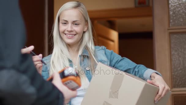 Mulher Sorrindo Recebe Pacote Postal após Assinar Dispositivo de Assinatura Eletrônica enquanto está no Portão Aberto — Vídeo de Stock