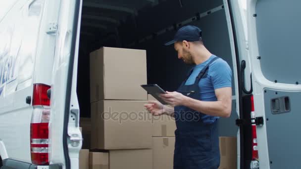 Delivery Man met een Tablet glimlachend controleert zijn lading graaf. — Stockvideo