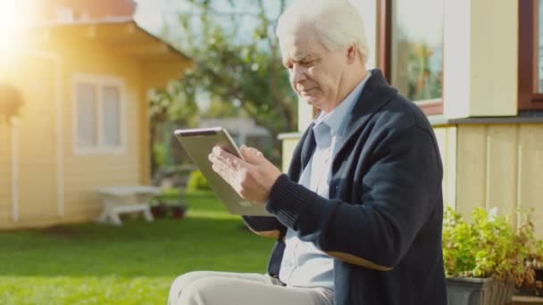 Starszy człowiek wykorzystuje komputer typu Tablet na zewnątrz. — Wideo stockowe