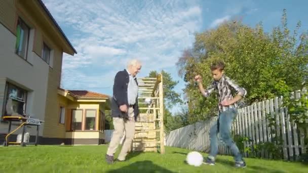 Opa en kleinzoon voetballen in de achtertuin. — Stockvideo