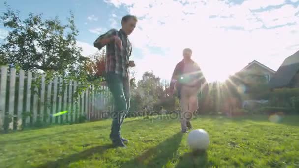 祖父と孫が裏庭をフットボールします。. — ストック動画