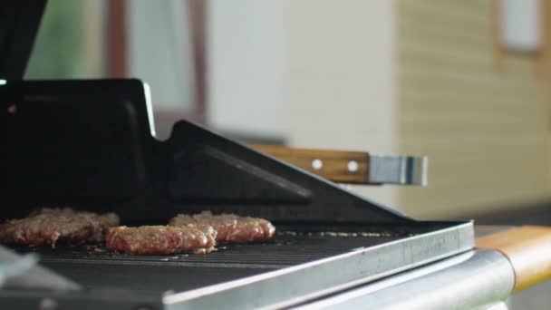 Close-up tiro de homem lançando hambúrgueres na grade — Vídeo de Stock