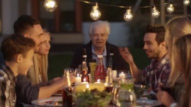 Bir grup insan yeme, iletişim ve Having Fun aile akşam yemeği sırasında bir masa etrafında oturup.