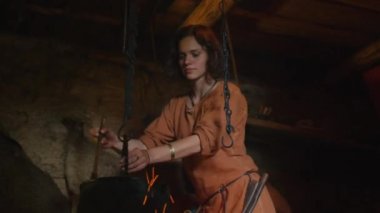 Yemek yanıyor Ortaçağ giyim kadın giyinmiş. Köyü'nde sivil insanların yaşam. Ortaçağ canlandırma.