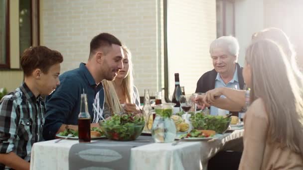 Vegyes verseny emberek szórakozás, kommunikáció és a szabadtéri családi vacsora eszik csoportja — Stock videók