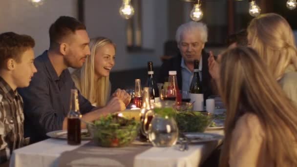 Skupina lidí, kteří sedí u stolu, jíst, komunikaci a Bavíte se během večeře rodinné sešlosti