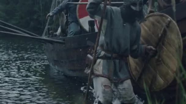 Viking krijgers springen uit het schip van de rij na Arriving naar de wal. Slaven en Vikingen Festival. Middeleeuwse re-enactment. — Stockvideo