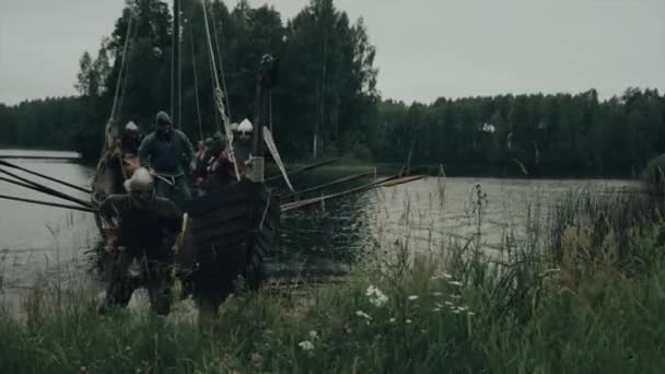 I guerrieri vichinghi saltano dalla nave di fila dopo essere arrivati a riva. Slavi e vichinghi Festival. Rievocazione medievale . — Video Stock