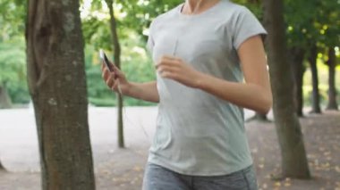 Parlak güneşli bir günde parkta çalıştırırken cep telefonu kullanan kadın