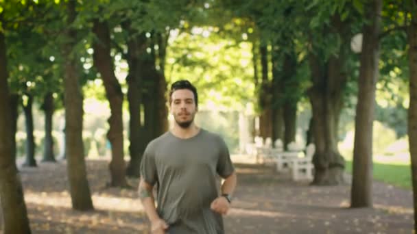 Молодой красавчик с помощью умных часов во время утренней пробежки в парке — стоковое видео