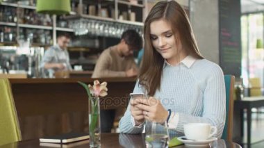 Çekici genç kadın sıcak kahve dükkanında istimal hareket eden telefon.