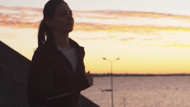 Γυναίκα τζόκινγκ κατά μήκος της ακτής κατά το ηλιοβασίλεμα — Αρχείο Βίντεο
