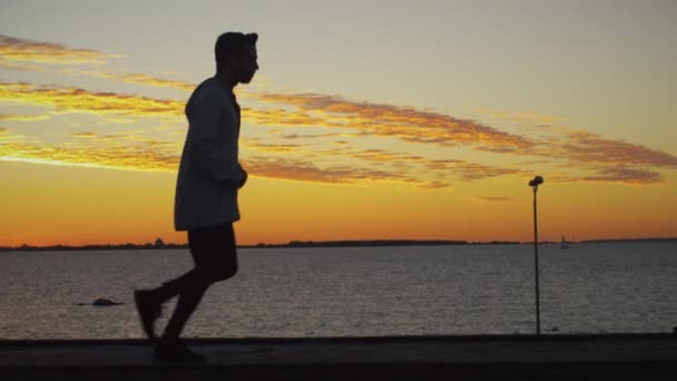 Muž zaběhat podél pobřeží při západu slunce — Stock video