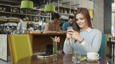 Çekici genç kadın sıcak kahve dükkanında istimal hareket eden telefon.