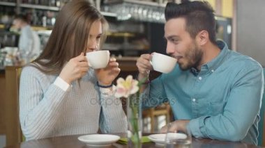 Çekici genç adam ve kadın oturuyor, rahat kafe konuşuyor musunuz.
