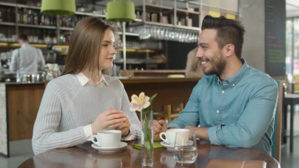 Atractivo joven y mujer están sentados hablando en acogedora cafetería . — Vídeo de stock