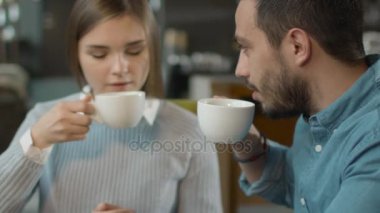 Çekici genç adam ve kadın oturuyor, rahat kafe konuşuyor musunuz.