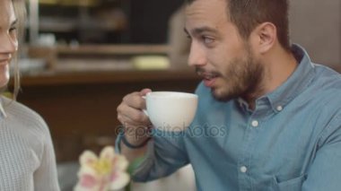 Çekici genç adam ve kadın oturuyor, rahat kafe konuşuyor musunuz.