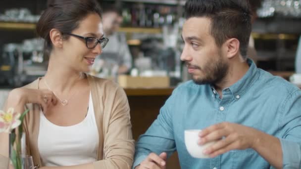 Atraktivní mladý muž a žena jsou sedí mluví v útulné kavárně. — Stock video