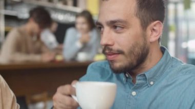 Çekici genç adam ve kadın oturuyor, rahat kafe konuşuyor musunuz.