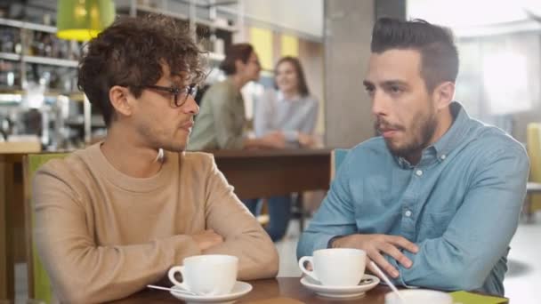 Sıcak kahve dükkanında konuşurken iki genç adam — Stok video