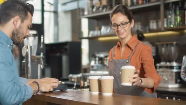 コーヒー ショップでの携帯電話でテイクアウト コーヒーを払ってハンサムな若い男. — ストック動画