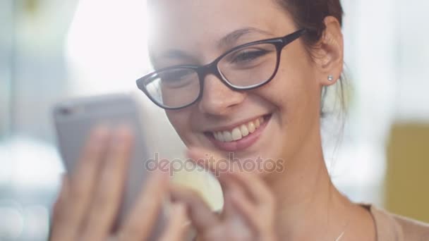 Καυκάσιος εθνότητα χαμογελώντας νεαρή γυναίκα χρησιμοποιώντας το κινητό τηλέφωνο στο άνετο κατάστημα καφέ. — Αρχείο Βίντεο