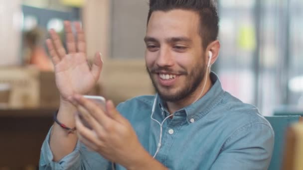 Junger Mann nutzt Handy für Video-Chat im Café. — Stockvideo