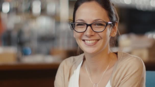 Portret atrakcyjne uśmiechający się młoda kobieta w przytulnej kawiarni. — Wideo stockowe