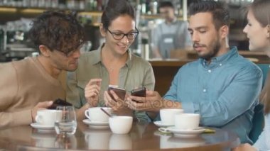 Grup genç karışık ırk kahve dükkanında telefonlarını kullanan insanlar.