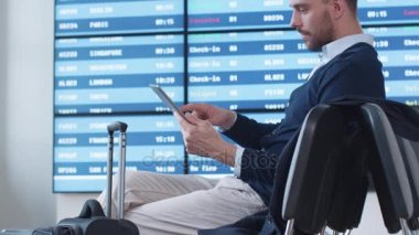 Tablet bekleyen biniş sırasında gidiş salonunda havaalanında kullanan adam.
