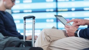 Tablet bekleyen biniş sırasında gidiş salonunda havaalanında kullanan adam.