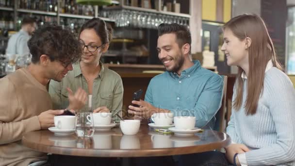 Gruppo di giovani di razza mista che utilizzano i telefoni in Coffee Shop . — Video Stock