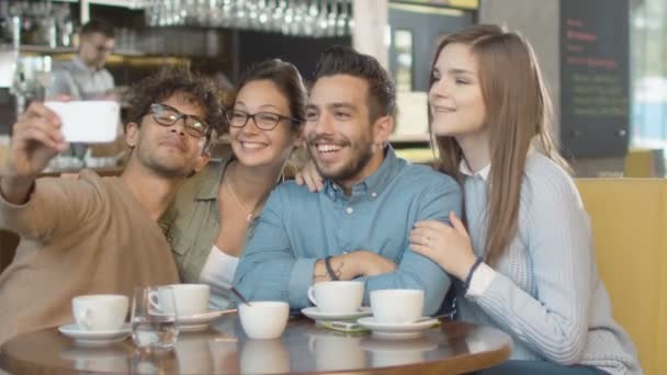 Группа молодых улыбающихся смешанной расы людей, делающих селфи с телефоном в кафе . — стоковое видео