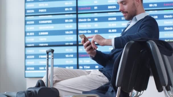 Hombre usando el teléfono mientras espera el embarque en la sala de embarque en el aeropuerto . — Vídeos de Stock