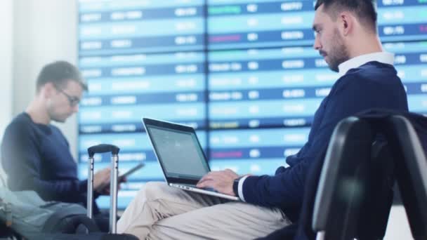 Uomo che lavora al computer portatile in attesa di imbarcarsi presso la sala partenze dell'aeroporto . — Video Stock