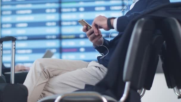 Человек слушает музыку во время ожидания посадки в зале вылета в аэропорту . — стоковое видео