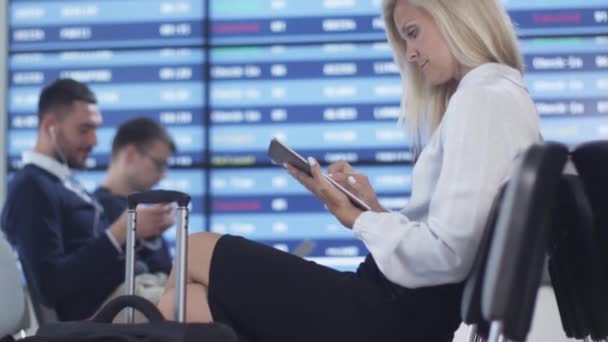 Çekici yetişkin iş Tablet bilgisayar süre bekleyen yatılı havaalanında gidiş salonunda kullanan kadın. — Stok video